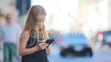 可爱的小女孩与智能手机温暖的一天户外欧洲城市
